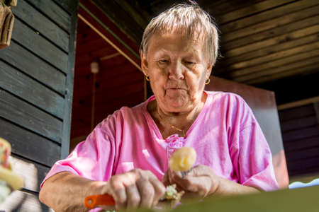 Senior woman pealing potatoes.の写真素材