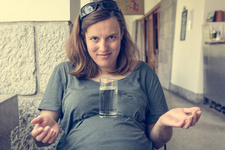 Pregnant woman having fun balancing a glass on her belly.の写真素材
