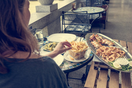 Female eating sea food at outdoor restaurant.
