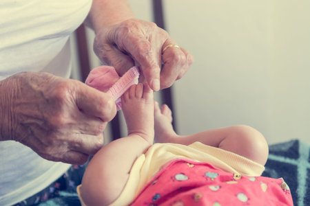 Closeup of elderly hands putting socks on newborn feet.