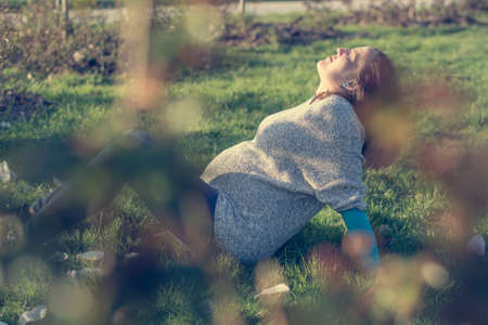 Expecting mother lying on grass in public park.の写真素材
