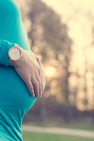 Closeup of pregnant belly at sunset.