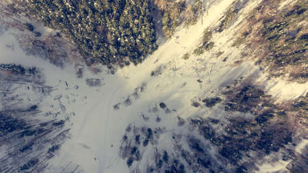 Drop down view of road going through winter forest.の写真素材