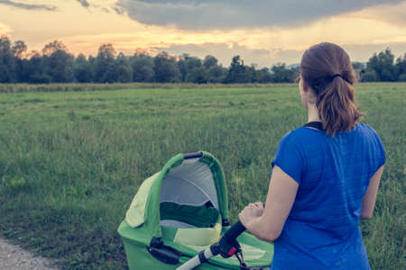 Active mom pushing a stroller at sunset.の写真素材