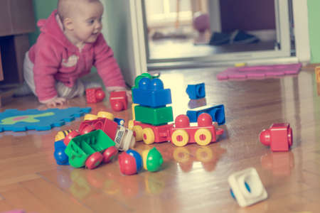 Baby playing with colorful bricks on wooden floor.の写真素材