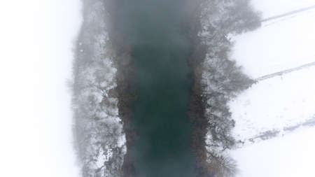 Snow surrounding a river covered by mists.の写真素材