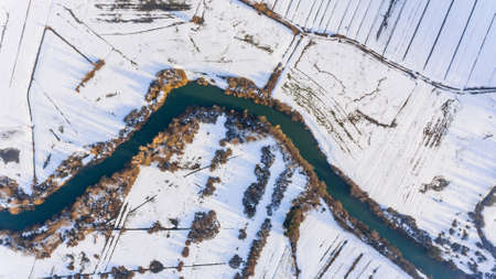 Aerial view riverbend passing snow covered fields.の写真素材