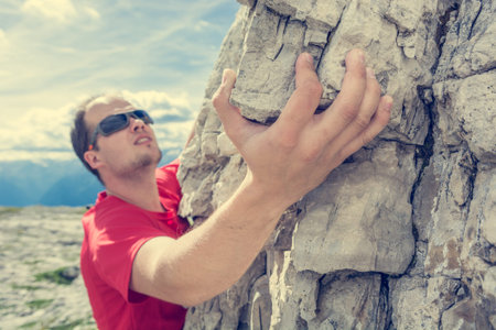 Closeup of climbers hand gripping a rock.