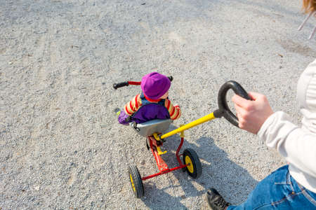 Mother pushing her child on a tricycle.の写真素材