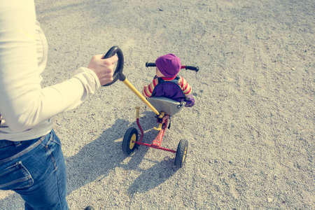 Mother pushing her child on a tricycle.の写真素材