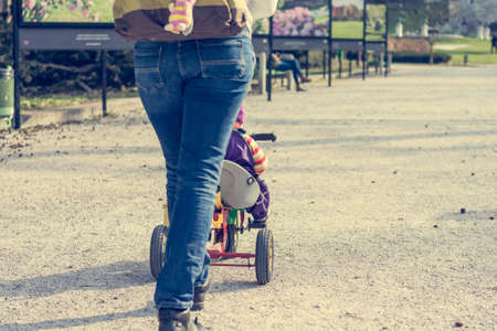 Mother pushing her child on a tricycle.の写真素材