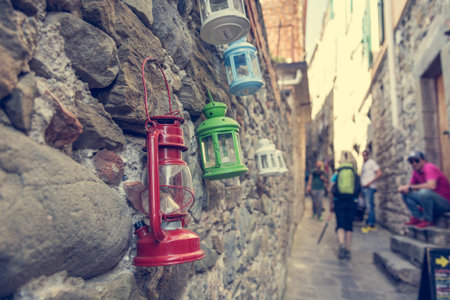 Colorful petroleum lamps hanging from a wall in narrow street.