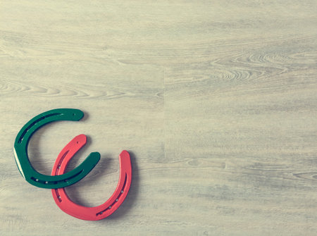 Pair of green and red horseshoes on a wooden desk.の写真素材