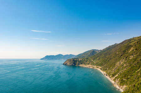 Ocean view with sun illuminating curvy coastline with hills. Cinque terre, Italy.の写真素材