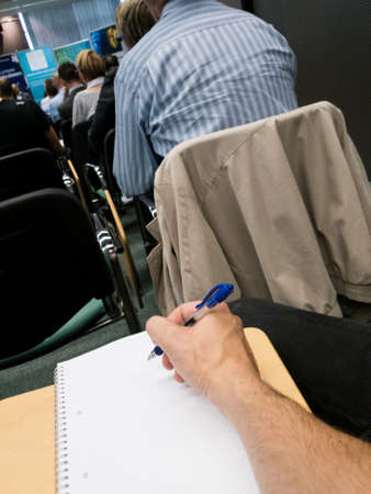 Taking notes at a conference with blue pen.の写真素材
