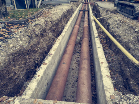 Metal pipes layed into concrete trench outdoor.