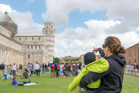 Mother carrying a child showing the Leaning tower of Pisa.の写真素材