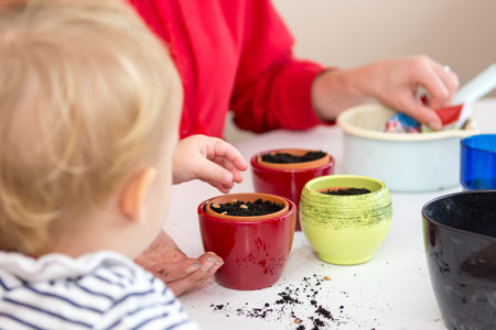 Closeup of child planting seeds into small pots.