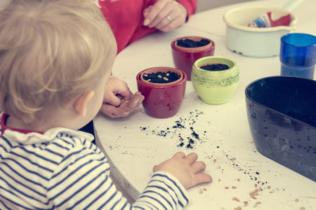 Closeup of child planting seeds into small pots.