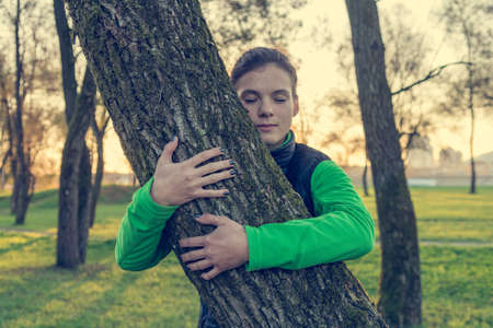 Portrait of caucasian female holding a tree trunk.の写真素材