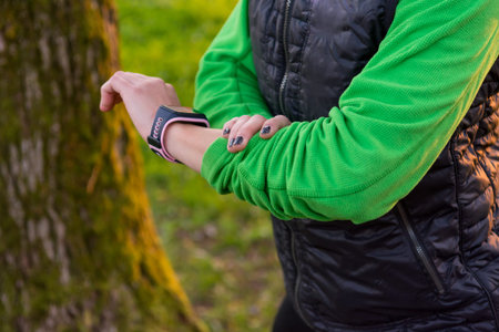 Closeup of female hands checking smart watch while exercising in a park.