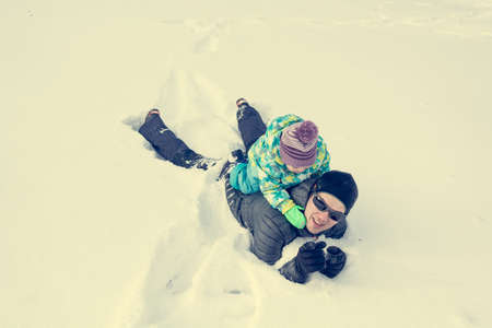 Father and daughter playing in fresh snow.の写真素材
