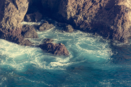 Waves crashing into spectacularly shapped vulcanic coastline.