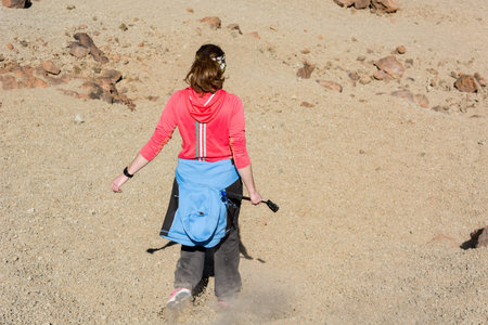 Sporty woman running down volcanic slope lifting dust trail.の写真素材