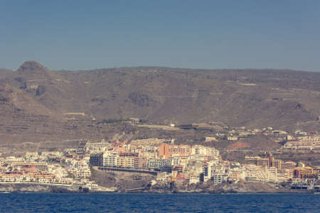Ocean port town situated under sheer cliffs - view from boat.の写真素材