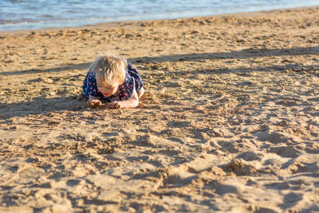 Cute little girl playing on sandy beach and exploring.の写真素材