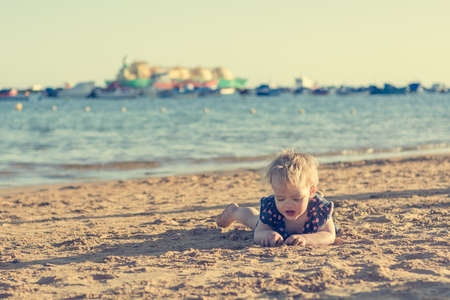 Cute little girl playing on sandy beach and exploring.の写真素材