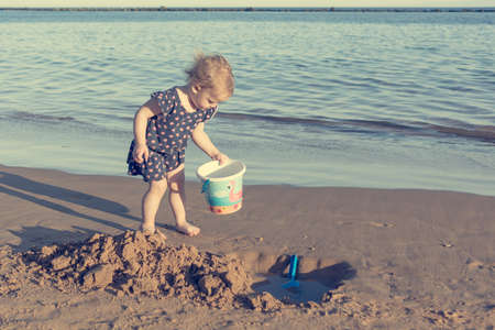 Cute little girl playing on sandy beach and exploring.の写真素材
