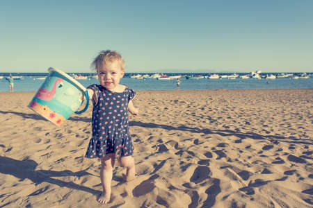 Cute little girl playing on sandy beach and exploring.の写真素材