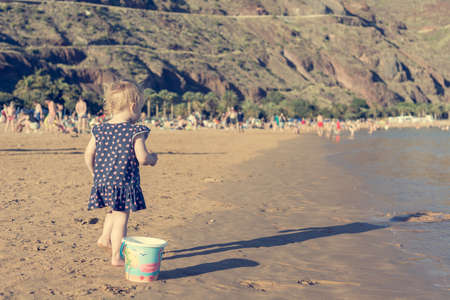 Cute little girl playing on sandy beach and exploring.の写真素材