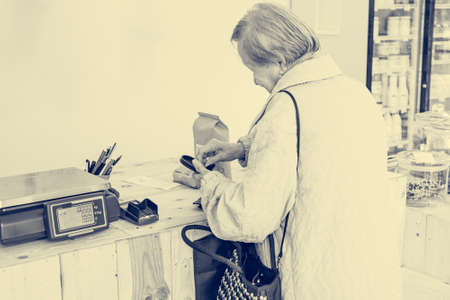 Elderly lady paying for some organic products at the counter of store.の写真素材