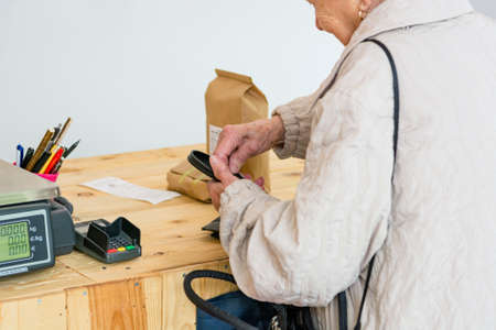 Elderly lady paying for some organic products at the counter of store.の写真素材