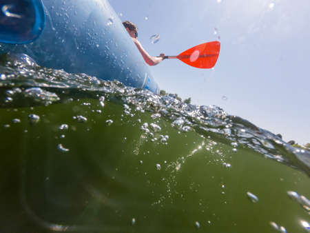 Split view of unrecognizable female rower in inflated boat rowing.の写真素材