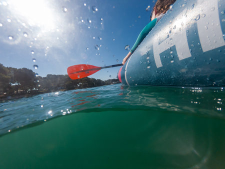 Split view of unrecognizable female rower in inflated boat rowing.