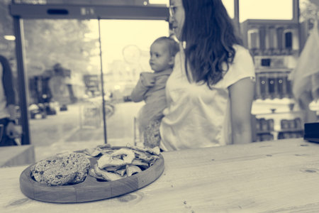 Cute adorable girl trying cookies at organic store with her mother.