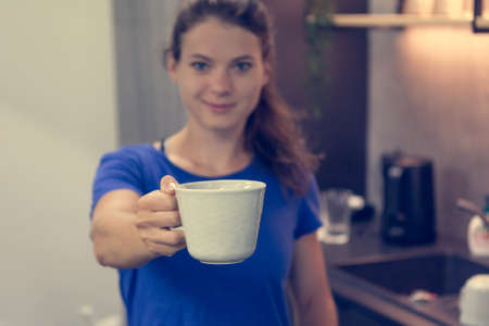 Female fitness assistant greeting you at homely gym bar with a cup of organic tea.の写真素材