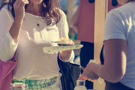 Customer trying local and organic products at outdoor market.の写真素材