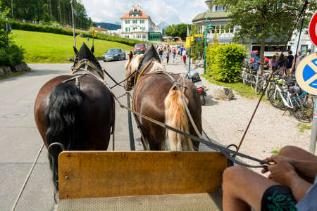 Riding a carriage pulled by a pair of horses.の写真素材