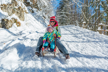 Mother and daughter speeding downhill on wooden sledge.