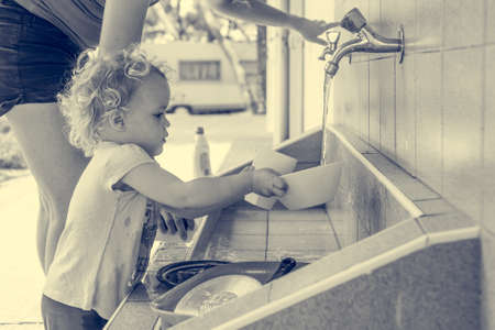 Little girl helping with the dishes outdoor.の写真素材