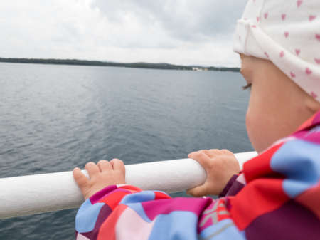Rear view of a cute girl enjoying a ferry ride in cloudy weather.の写真素材