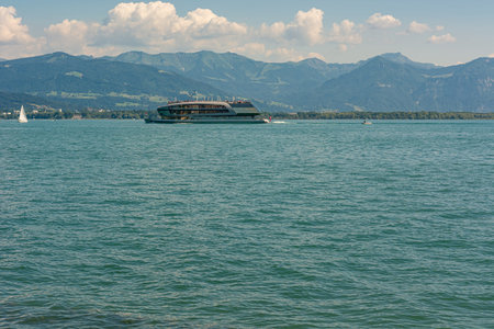 Luxury boat sailing mountain lake on sunny day.