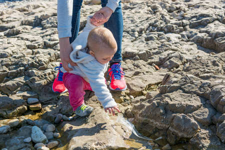 Cute blonde baby girl exploring beach in a sunny weather.の写真素材