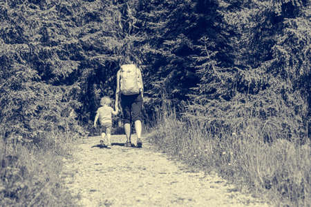Mother and daughter hiking on a forest path.の写真素材