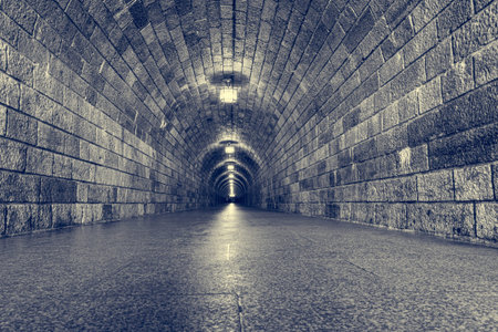 Tunnel running through mountain illuminated with electric lights.