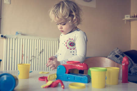 Cute girl playing with many colorful doughs.の写真素材
